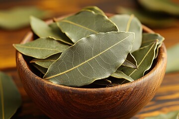 Dried bay leaves in a rustic wooden bowl displayed on a kitchen countertop with a warm atmosphere
