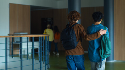 Two boys students pupils walking in corridor go to lesson in school university college meeting...
