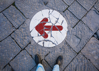 A person is standing in front of a Broken White Marble Slab. It has a circular shape and there is a sign of continuing with an arrow pointing to the left. Guide, Decision and turning or Going Concept