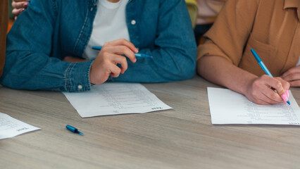 Unrecognizable cropped view close up school Caucasian students learn pupils studying male female write homework teamwork at table study learning men women girls guys writing college test exam write © Yuliia
