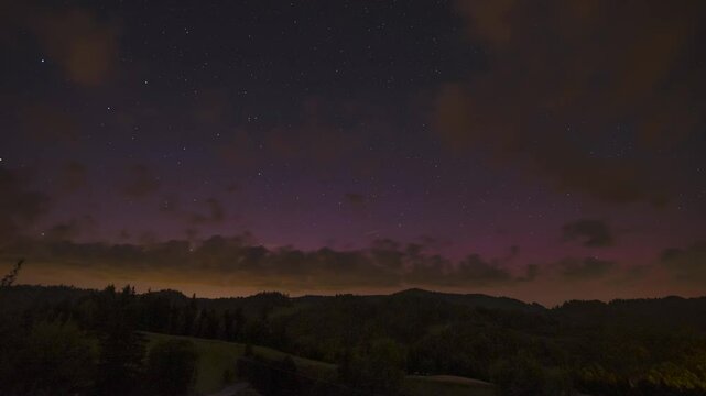 Aurora Borealis over mountains and clouds - timelapse