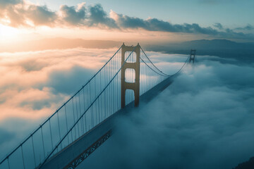 Fototapeta premium Elevated view of a bridge emerging from clouds at sunrise over a mountainous landscape