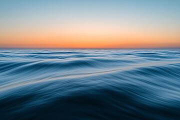 Obraz premium Sunset over calm ocean waters creates a serene atmosphere with vibrant colors on the horizon