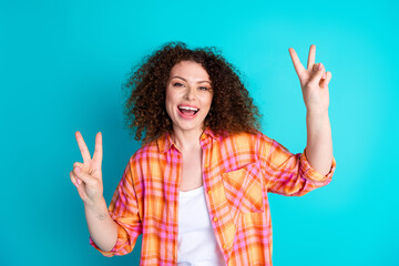 Cheerful young woman in trendy outfit showing joyful gestures on turquoise background