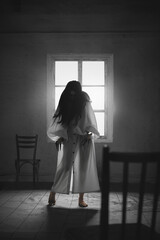 Inner anger. Supernatural witch,terrifying woman in long white gown and dark hair standing in room...