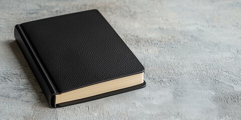 A sleek black book rests on a textured surface, showcasing its minimalist design and elegant craftsmanship.