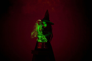 Mysterious witch lifts skull from steaming cauldron, with green mist rising around, in a dimly lit...
