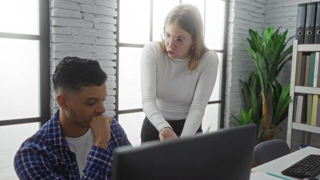 Woman discussing work with man in modern office interior, surrounded by brick walls and bright light, reflecting a serious business environment with visible tension between colleagues.