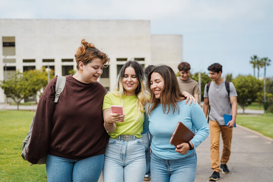 Young group of students having fun outdoor using smartphone while walking in university campus - Back to school concept - Main focus on center girl face