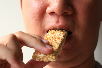 Close up view of Young Asian man eating healthy granola bar honey  flavor. wellness concept