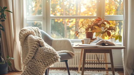 Cozy living room with a knitted blanket draped over a chair, warm sunlight streaming through windows, autumn foliage outside