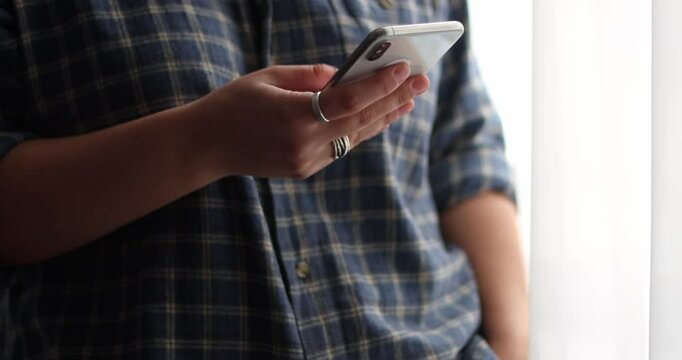 Female's hands scroll mobile phone, texting, chat and correspond keypad to check messages at home in evening 
