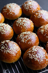 A number of homemade burger buns resting on a cooling tray