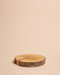 Natural wooden pedestal podium with bark edges on a neutral beige background. Ideal for product...