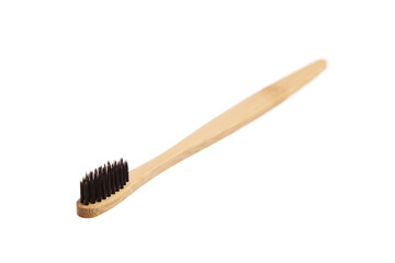 A biodegradable bamboo toothbrush with black bristles, featuring a smooth wooden handle, isolated on a white background. Ideal for eco-friendly oral care