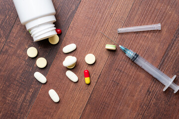 Scattered Pills and Syringe on Wooden Table