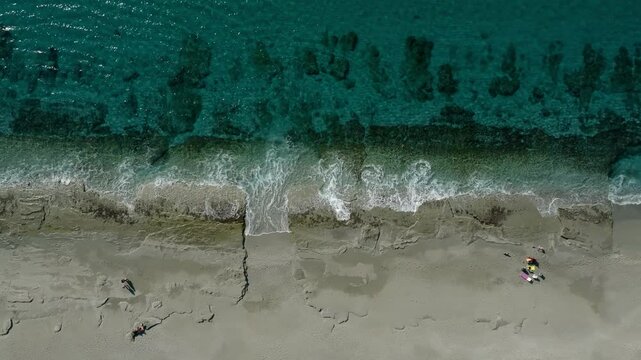  Aerial top down view of a stone passage leading to turquoise sea with waves on a sandy beach in Mahmutlar, Alanya, Turkey