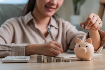 Asian woman hand put coins in piggy bank,Saving money wealth and financial concept. 