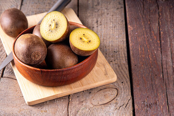 Sweet golden kiwi fruits, whole and sliced, on kitchen table copy space