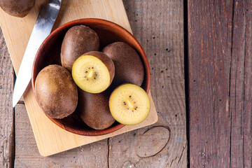 Sweet golden kiwi fruits, whole and sliced, on kitchen table copy space