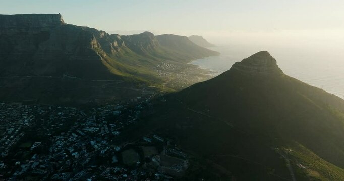 Aerial panorama of Cape Town at sunset, surrounded by ocean and city districts, South Africa. Majestic landscape of Signal Hill and Lions Head Peak in Table Mountain. 4K Establishing wide drone shot