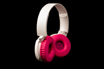 Pink and white headphones isolated on a black background.