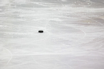 Small Black Ice Hockey puck laying on skated ice.