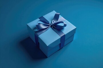 Obraz premium Blue gift box with a ribbon tied around it on a dark blue background, wrapping paper, packaging, decorative element