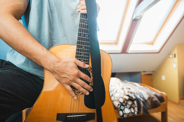 Close-up perspective of an acoustic guitar being played, with fingers pressing the fretboard,...