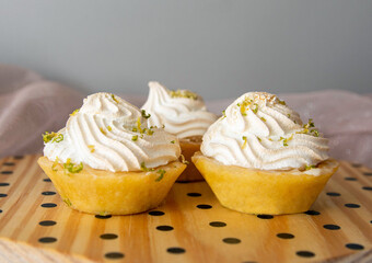 Wooden tray with three small lemons pies on it. Traditional sweet sold in the city of Pelotas, Rio Grande do Sul, Brazil. Aromatic lemon mini cakes with cream on top. Delicious desserts.