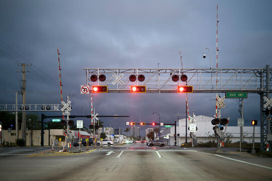 Road intersection with red traffic lights and railway crossing at dusk, Miami, Florida, USA