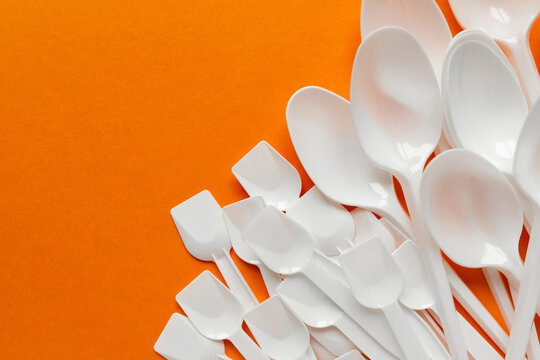 white plastic disposable cutlery on orange bachground (tablespoons, teaspoons)
environmental problem 