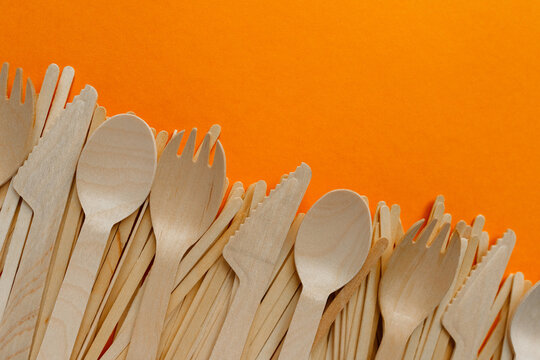 wooden disposable cutlery - knives, forks, tablespoons, stirrers on orange bachground
environmental problem 