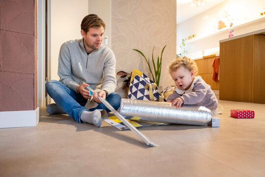 Man and toddler engaged in a home DIY project, sitting on a living room floor. Netherlands