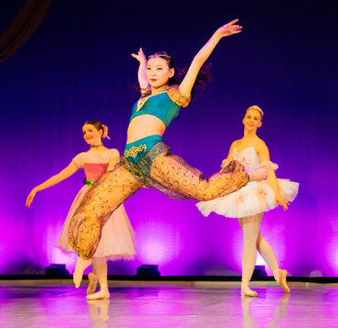 Dancers performing on stage in colorful costumes with a vibrant purple backdrop. The Nutcracker, Bainbridge Island, USA