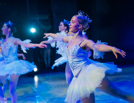 Ballet dancers in white tutus perform on stage in dramatic blue lighting. The Nutcracker, Bainbridge Island, USA