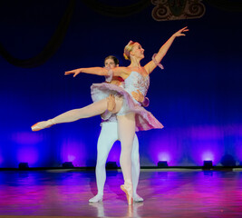 Ballet dancers performing on stage in elegant costumes with a vibrant lit backdrop. The Nutcracker, Bainbridge Island, USA