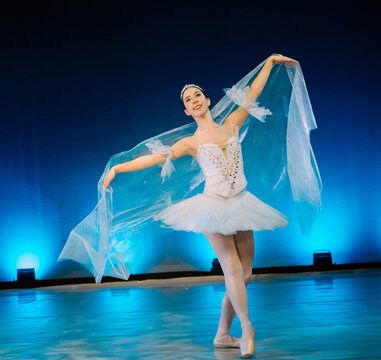 Ballet dancer in a white tutu gracefully performs on stage with blue lighting. The Nutcracker, Bainbridge Island, USA