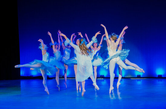 Ballet dancers in flowing blue costumes performing energetically on a stage with blue lighting. The Nutcracker, Bainbridge Island, USA