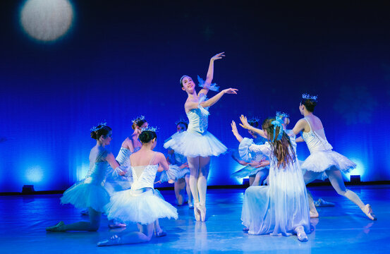Ballet dancers in white tutus perform gracefully on a stage with blue lighting. The Nutcracker, Bainbridge Island, USA