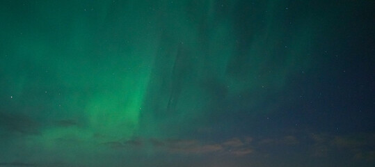 Stunning green aurora borealis over dark horizon.