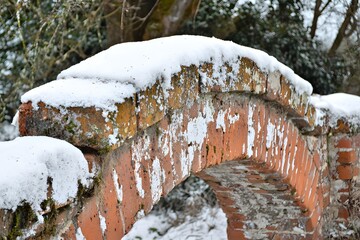 Fototapeta premium Snow-Dusted Brick Archway: A charming brick archway is beautifully adorned with a blanket of fresh snow, creating a picturesque winter scene.