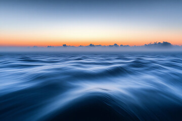 Obraz premium Sunset over calm ocean waters creates a serene atmosphere with vibrant colors on the horizon
