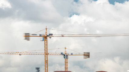 Big construction site including several cranes working and moving on a building complex, with...