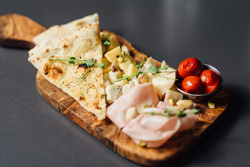 Close up of Italian antipasti platter featuring aged cheeses, prosciutto, olives, and focaccia, served with lavender honey. Perfectly paired with red wine. 
