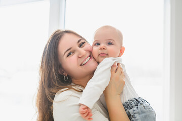 portrait of happy young mother and infant girl on bedroom