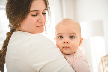 Cute small baby girl in bed at home. Woman holding little infant child.