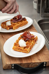 Chef pouring sauce on a savory brisket waffle breakfast