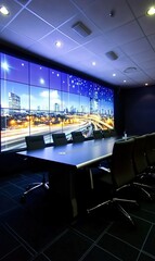 Modern conference room with large video wall displaying city nightscape, ideal for business meetings