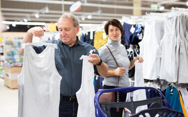 Elderly man and elderly woman choose t-shirt